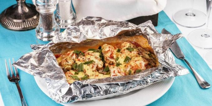 Fish baked in foil with tomatoes, cheese and mushrooms