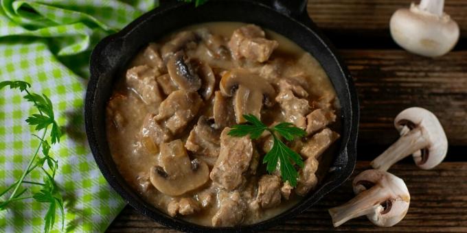 Pork with champignons in sour cream and cheese sauce