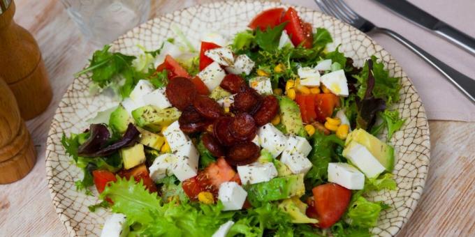 Salad with fried sausages, cheese, tomatoes and avocado