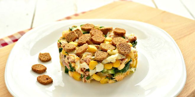 Salad with crackers, salmon, corn and cucumber