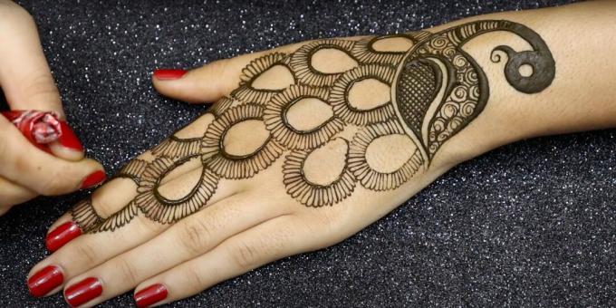 Draw the peacock's tail with henna on the hand